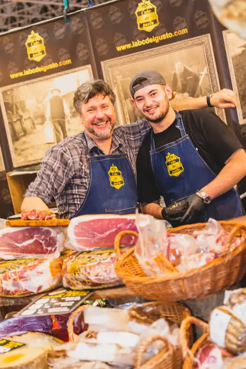 Portrait de deux exposants, sur un stand de charcuterie