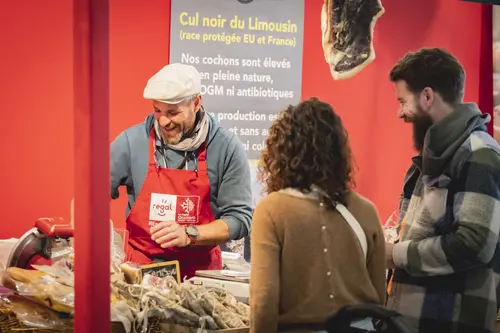 Un exposant coupe de la charcuterie pour des visiteurs